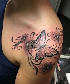 a woman's shoulder with flowers and a butterfly tattoo on her left side breast