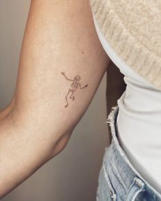 a woman's arm with a small skeleton tattoo on the left side of her arm