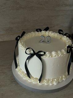 a white cake with black ribbons and the number 20 on it