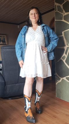 a woman wearing cowboy boots standing next to a couch