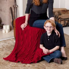 a woman sitting on the floor next to a little boy who is smiling at the camera