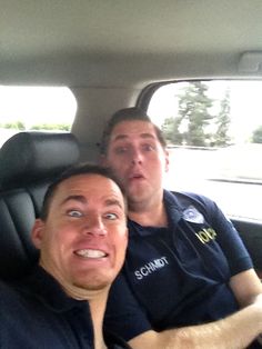 two men sitting in the back seat of a car, one with his mouth open