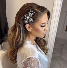 a woman with long hair wearing a white blouse and a flower clip in her hair