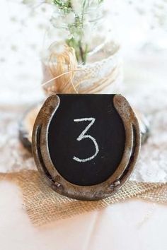 a chalkboard with the number three on it sitting next to a vase filled with flowers