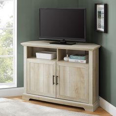 a flat screen tv sitting on top of a wooden entertainment center next to a window