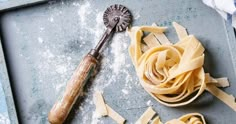 some pasta on a tray with a rolling pin and other food items around the edges