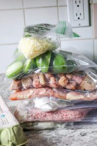 meat and vegetables wrapped in plastic sitting on top of a counter