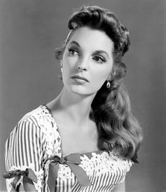 an old black and white photo of a woman with long hair wearing a striped dress