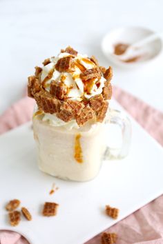 a dessert in a glass on top of a white plate with pecans around it