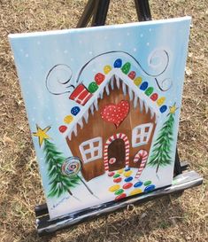 an easel painted with a gingerbread house and candy canes in the snow