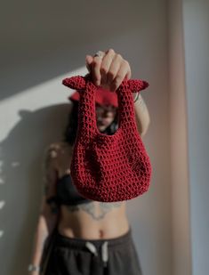 a woman is holding up a red bag