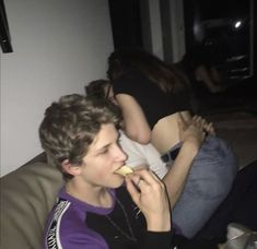 two people sitting on a couch eating food