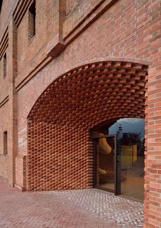 a brick building with an arched doorway and glass door on the outside, surrounded by red bricks