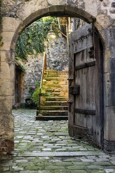 an old stone building with stairs leading up to the door and through which is a light fixture