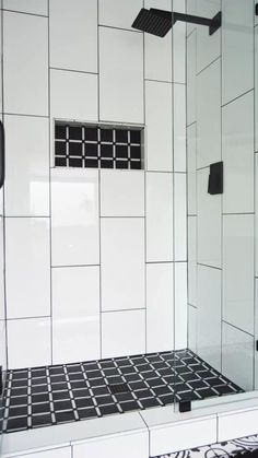 a bathroom with black and white tiles on the shower wall