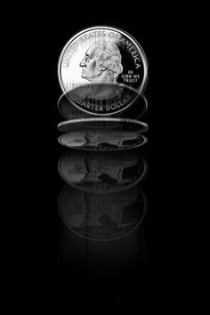 an american silver dollar is shown in this black and white photo, with its reflection on the ground