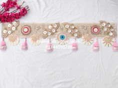 a white table cloth with pink tassels and beads on it, next to a bouquet of flowers