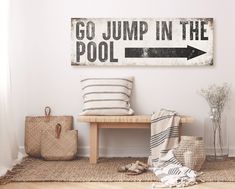 a sign that says go jump in the pool next to a bench with pillows on it