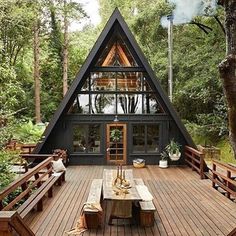 a large wooden deck with a picnic table and bench in front of a small cabin