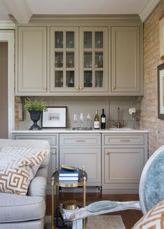 a kitchen with gray cabinets and white counter tops, wine glasses on the cabinet doors