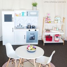 a white table with two chairs and a small oven in the corner next to it