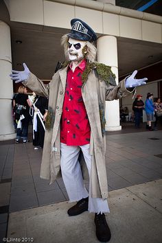 a man dressed up as a scarecrow standing in front of a building with his arms out