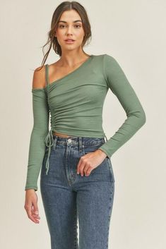 Final Sale - Get it before it's gone! Style the Lush Angie Olive One-Shoulder Ruched Crop Top with your favorite jeans for a fun weekend look! Rib knit fabric forms a one shoulder fitted bodice top with long sleeves and ruched detail. Drawstring tie at hemline finishes the look! DETAILS & CARE Rayon/Nylon/Spandex. Machine wash cold. Imported. Drawstring Ruched Top, Metallic Top Outfit, Olive Green Crop Top, College Outfits Fall, Christmas Outfit Aesthetic, Outfit Ideas College, Folklore Dress, Summer Wedding Gowns, Nyc Winter Outfits