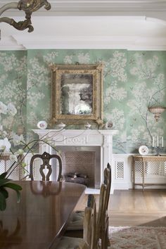 the dining room is decorated in green and white with flowers on the wall behind the fireplace