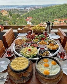 a table full of food on top of a wooden table with plates and bowls filled with food