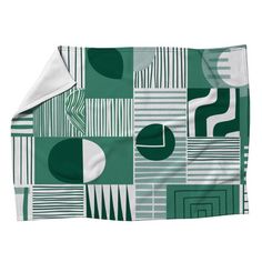 a green and white blanket with geometric shapes on the front, along with a white background