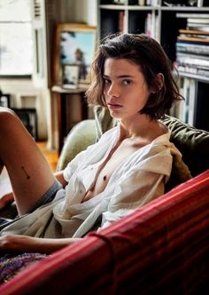 a woman sitting on top of a couch next to a book shelf