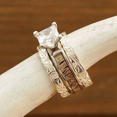 two silver rings with white stones sitting on top of a wooden table next to a cow's head