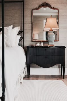 a bedroom with a bed, mirror and lamp on the side table in front of it