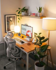 a desk with a computer, lamp and potted plant