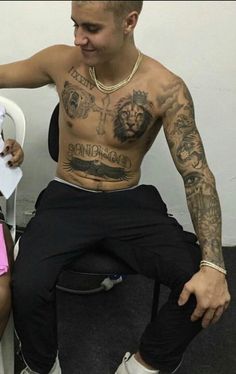 a man with tattoos sitting on top of a toilet