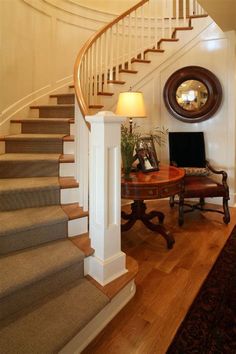 there is a table and chair in the room by the stairs with a mirror on it