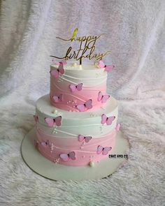 a three tiered cake with pink butterflies on it and a happy birthday topper