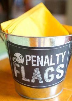 a metal bucket filled with yellow napkins on top of a wooden table