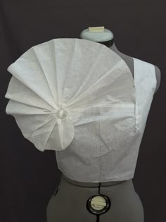 a mannequin's torso is covered in white paper with a circular object attached to it