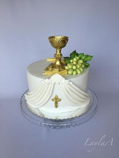 a cake decorated with grapes and a gold chalicette on top is sitting on a glass platter