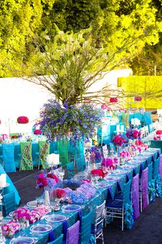 the tables are covered with blue, purple and green linens as well as flowers