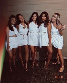 a group of women in white dresses posing for a photo