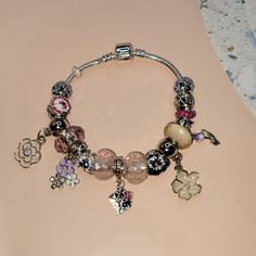 a close up of a bracelet on a table with flowers and charms attached to it