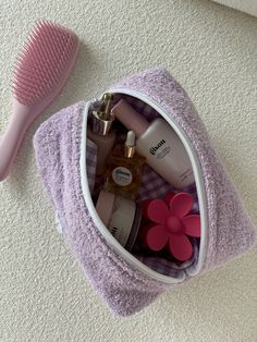 a pink hair brush and some personal care items in a purple bag