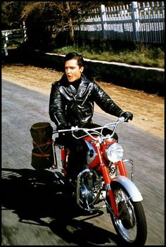 a man riding on the back of a red motorcycle