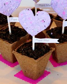 four planters with hearts on them and plants in the middle one is made out of dirt