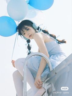 a woman in a blue dress holding balloons