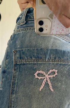 someone is holding their cell phone up to the back of her jean pants with a bow on it