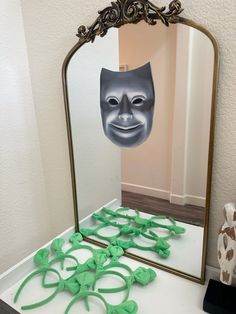 a mirror that has some green decorations in front of it and a mask on the mirror