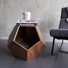 a chair and table with books on it in front of a concrete wall next to a gray chair